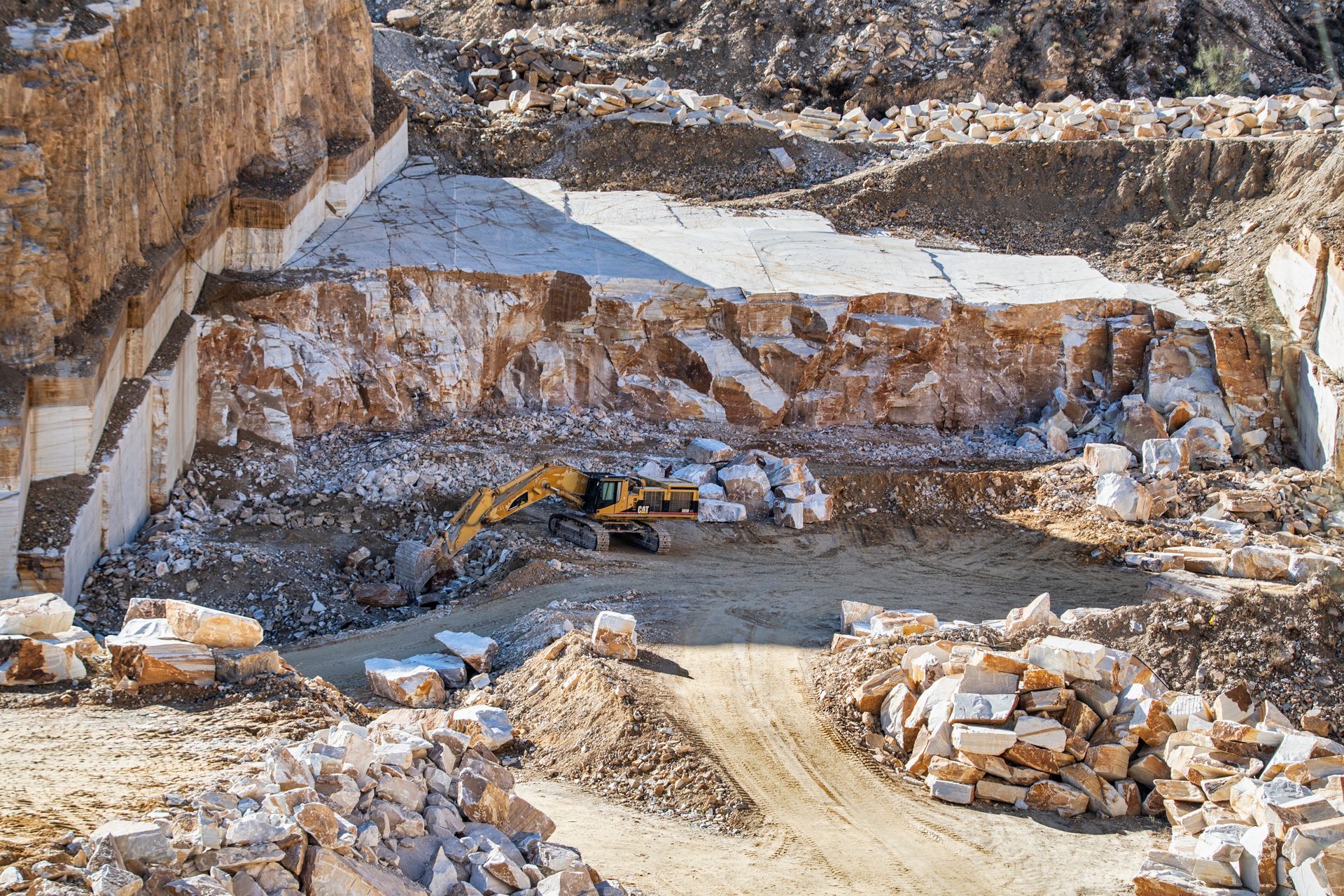 Excavator working in a warm-toned stone quarry